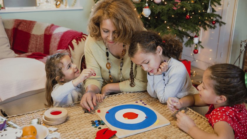 Gezeigt wird eine Oma mit drei Enkelinnen, die zusammen an Weihnachten ein Gesellschaftsspiel spielen.