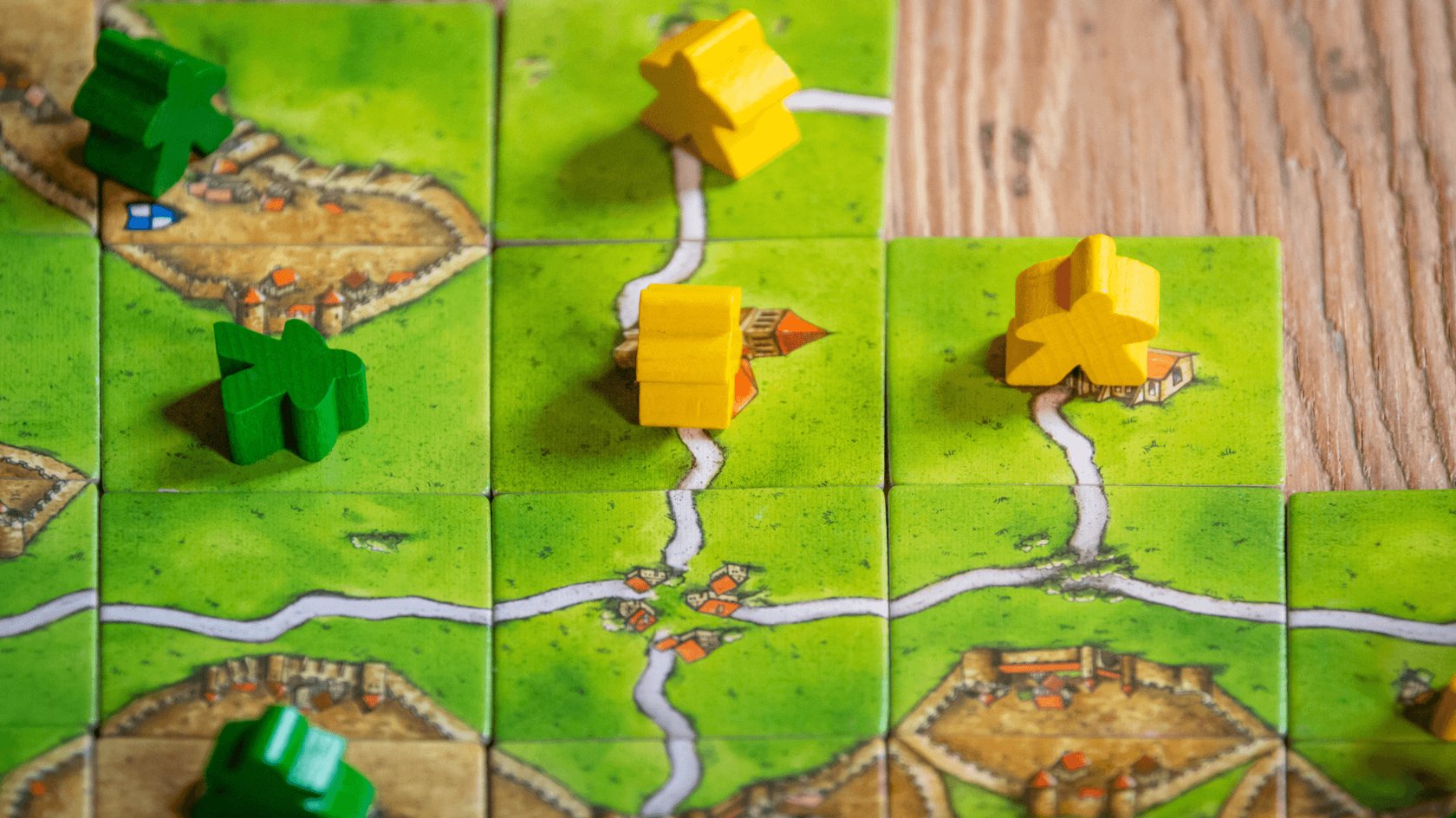 Gezeigt werden Spielplättchen und Spielfiguren aus dem Brettspiel Carcassonne.