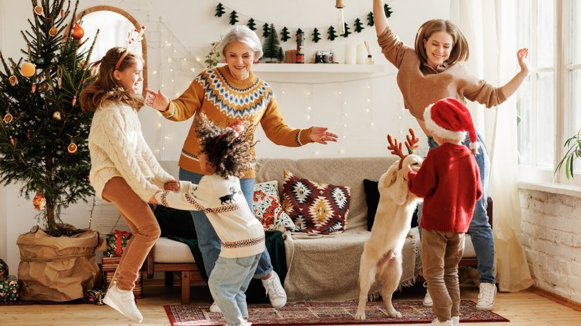 Gezeigt wird eine Familie, die in einem weihnachtlich geschmücktem Wohnzimmer tanzt.