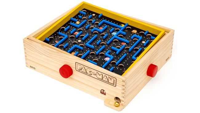 Das Bild zeigt ein PAC-MAN-Labyrinthspiel aus Holz. Das Spielfeld ist in einem Holzkasten mit gelbem Rand eingebettet. Auf dem Spielfeld befinden sich blaue Wände, die ein Labyrinth bilden, sowie PAC-MAN, Geister und Punkte. Das Spiel hat zwei rote Drehknöpfe an der Vorderseite zum Neigen des Spielfelds, um eine Kugel durch das Labyrinth zu führen. Auf der Vorderseite des Holzkastens ist das PAC-MAN-Logo eingraviert.