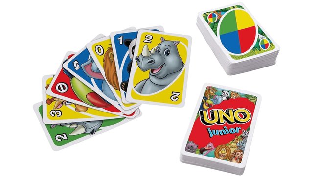 Das Bild zeigt das Kartenspiel "UNO Junior" mit bunten Karten, die neben Zahlen auch Tierillustrationen wie ein Nashorn, einen Löwen und einen Panda enthalten. Im Hintergrund liegen zwei Kartenstapel, einer mit der Rückseite des Spiels und einer mit einer Farbsymbol-Karte.