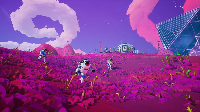 Das Bild zeigt eine Szene aus dem Spiel Astroneer. Mehrere Astronauten bewegen sich auf einer außerirdischen, violett-pinkfarbenen Landschaft mit futuristischen Strukturen und Pflanzen. Im Hintergrund sind ein rundes Gebäude und ein geometrisches Kuppelgebäude zu sehen. Der Himmel ist in lila Tönen gehalten, mit großen, wolkenartigen Formationen.