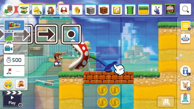 Das Bild zeigt den Bau-Modus von Super Mario Maker 2 im Super Mario 3D World-Stil. Mario steht vor einer riesigen Piranha-Pflanze, die sich auf einer Plattform mit Ziegelblöcken und darunterliegenden Münzen befindet. Oben ist eine Leiste mit verschiedenen Bauelementen wie Röhren, Blöcken und Gegnern sichtbar. Ein weißer Handschuh-Cursor platziert ein Objekt. Links sind Spielzeit (500 Sekunden), ein Startpunkt und ein Play-Button zu sehen.