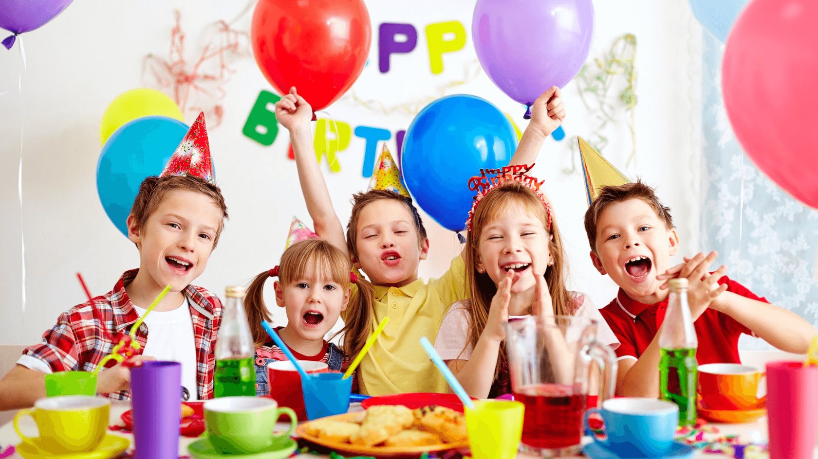 Gezeigt wird ein fröhlicher Kindergeburtstag mit fünf lachenden Kindern, die bunte Partyhüte tragen und von Luftballons umgeben sind. Der Tisch ist mit farbenfrohen Tassen, Tellern und Getränken gedeckt. Die Kinder wirken ausgelassen und feiern gemeinsam in einer fröhlichen Atmosphäre.