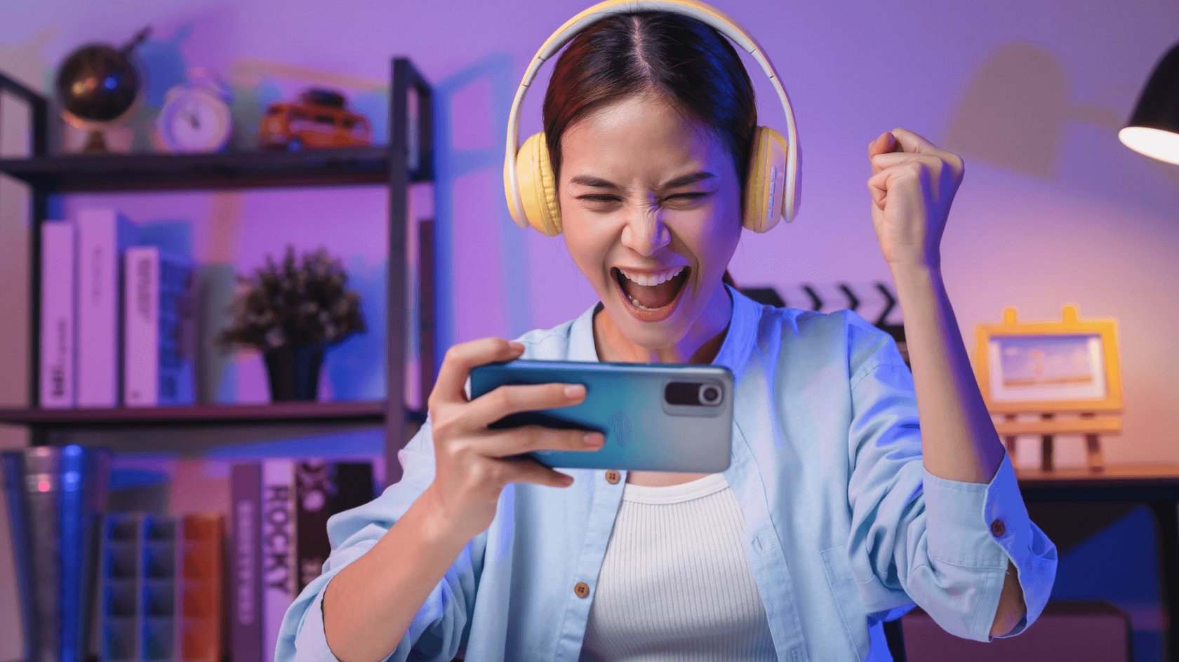 Gezeigt wird eine junge asiatisch aussehende Frau, die auf einem Smartphone Onlinespiele spielt.
