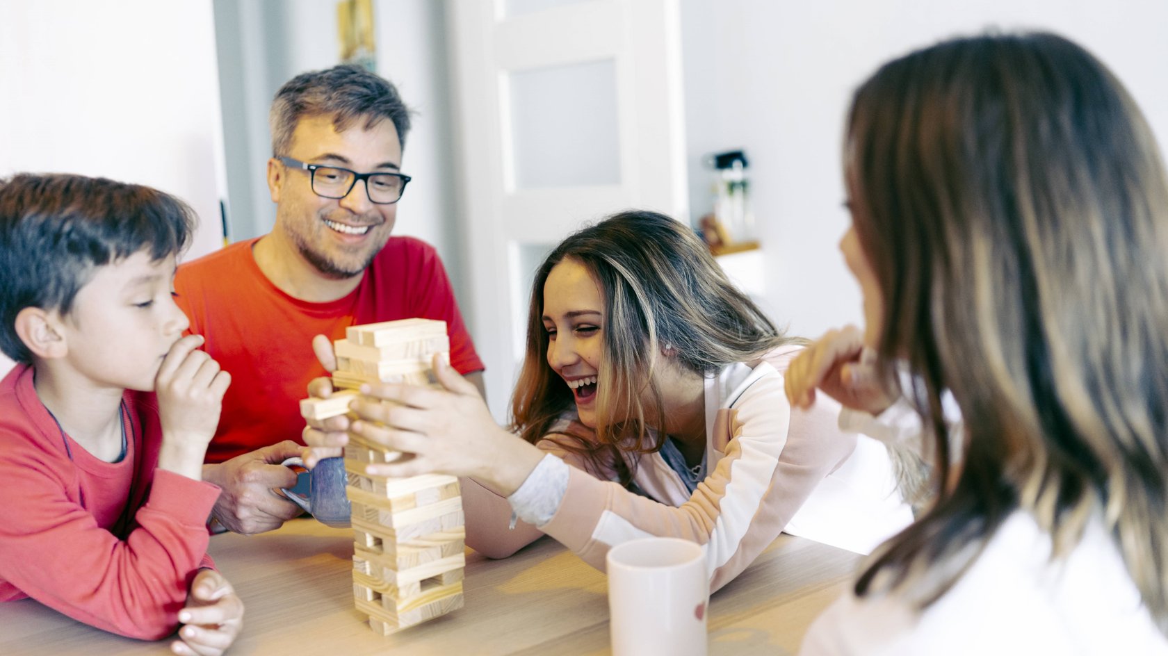 Gezeigt wird eine Familie, die einen Jenga-Turm abbaut.