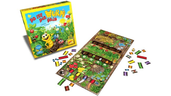 Das Bild zeigt das Brettspiel "Da ist der Wurm drin" von Zoch. Im Vordergrund ist das offene Spielbrett zu sehen, das bunt gestaltet ist und verschiedene Garten- und Erdreich-Motive zeigt. Um das Spielbrett herum liegen bunte Spielsteine und ein Würfel. Im Hintergrund steht die Spielverpackung, die eine fröhliche Illustration eines gelben Wurms und anderer Gartenbewohner auf einem bunten Blumenhintergrund zeigt.