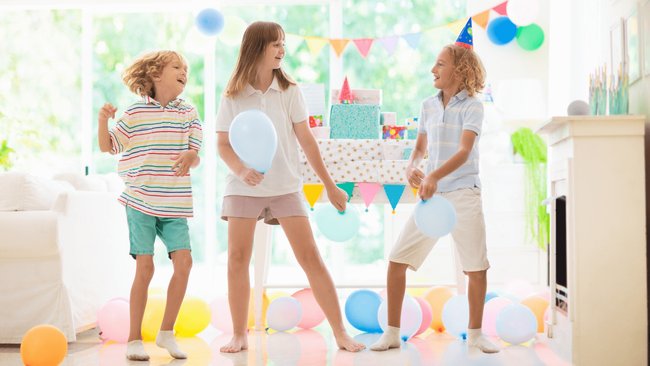 Gezeigt werden drei Kinder, die auf einer Party mit Luftballons spielen und sich dabei bewegen.