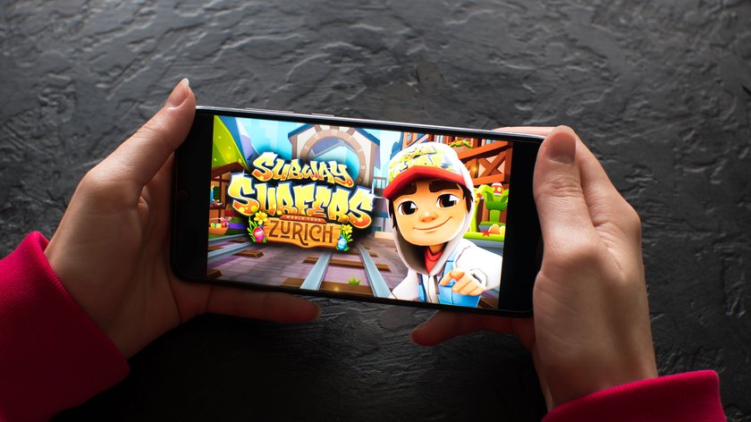 Zwei Hände halten ein Smartphone, auf dem eine Ansicht des Spiels Subway Surfers zu sehen ist.