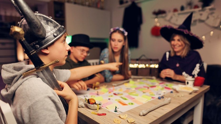 Eine Familie spielt an Halloween Brettspiele in Kostümen.