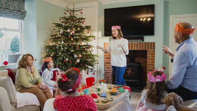 Eine Familie spielt am Weihnachtsabend Scharade in ihrem Wohnzimmer.